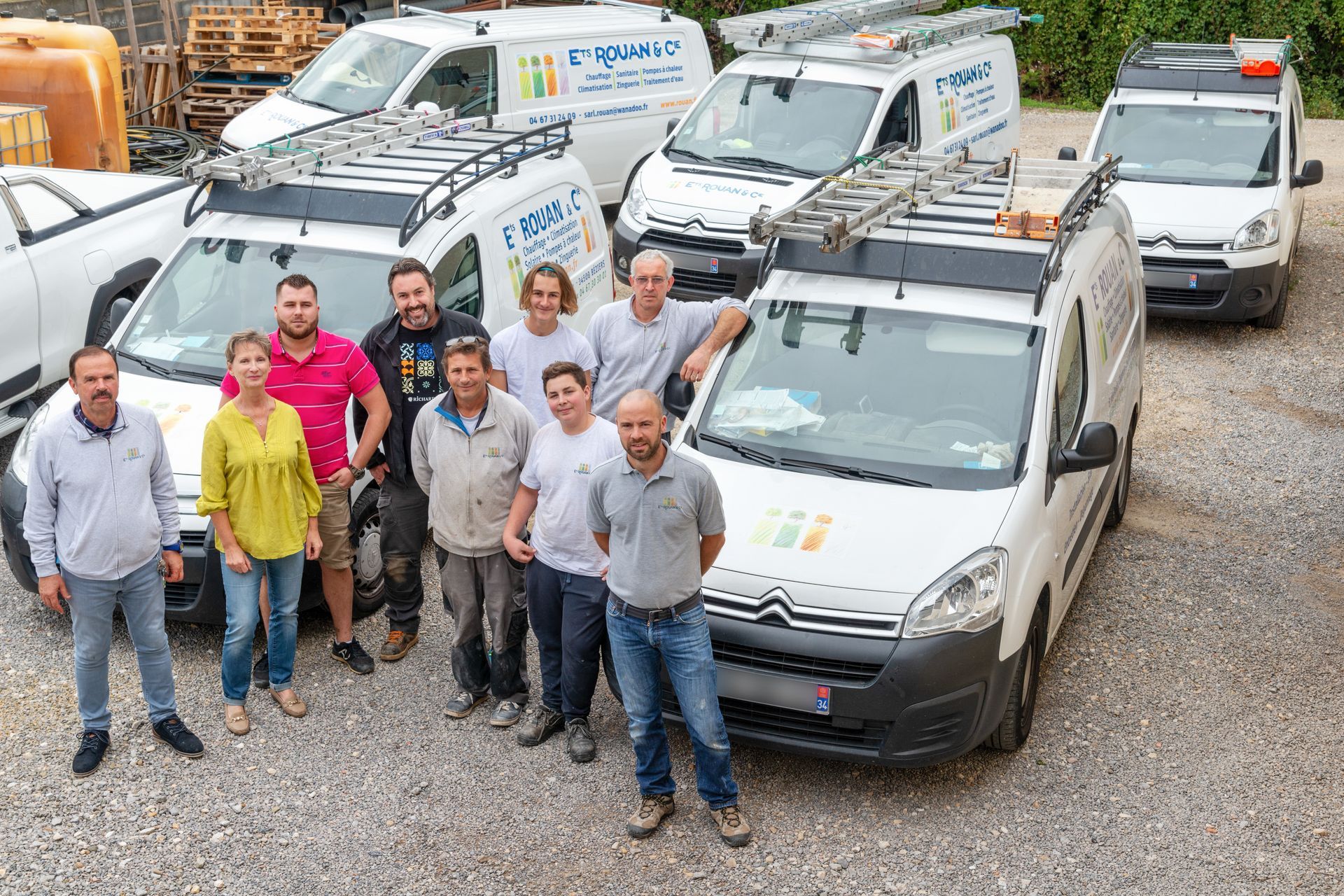 Équipe de l'entreprise prenant la pose devant des camionnettes