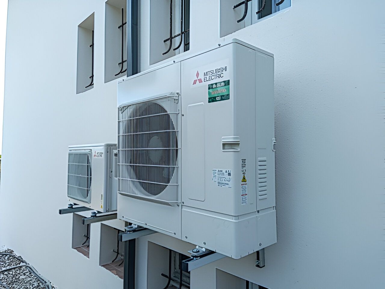 Une petite et une grande pompe à chaleur fixées à un mur extérieur