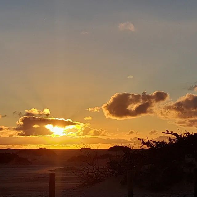 El sol se está poniendo sobre el océano con nubes en el cielo.