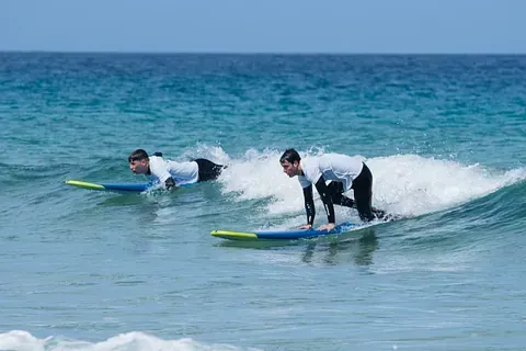 Dos hombres están montando olas en tablas de surf en el océano.