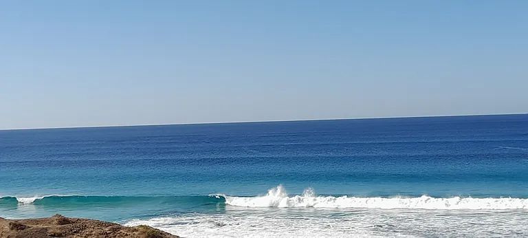 Una gran masa de agua con olas rompiendo en la orilla.