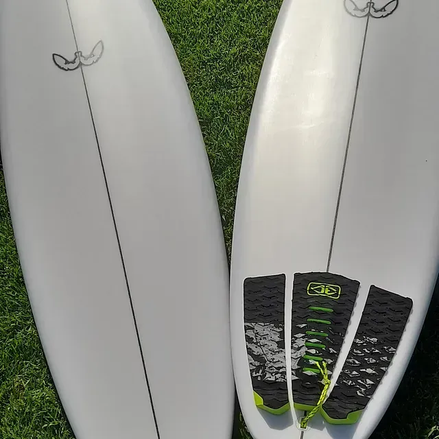 Hay dos tablas de surf sobre el césped y una tiene una pegatina que dice 