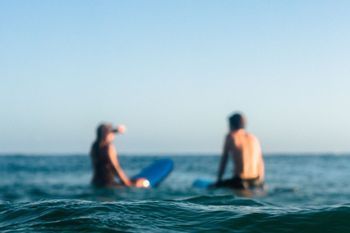 Un hombre y una mujer están sentados en una tabla de surf en el océano.