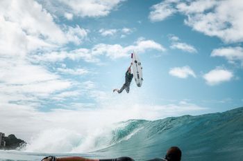 Un surfista está volando por el aire mientras monta una ola.