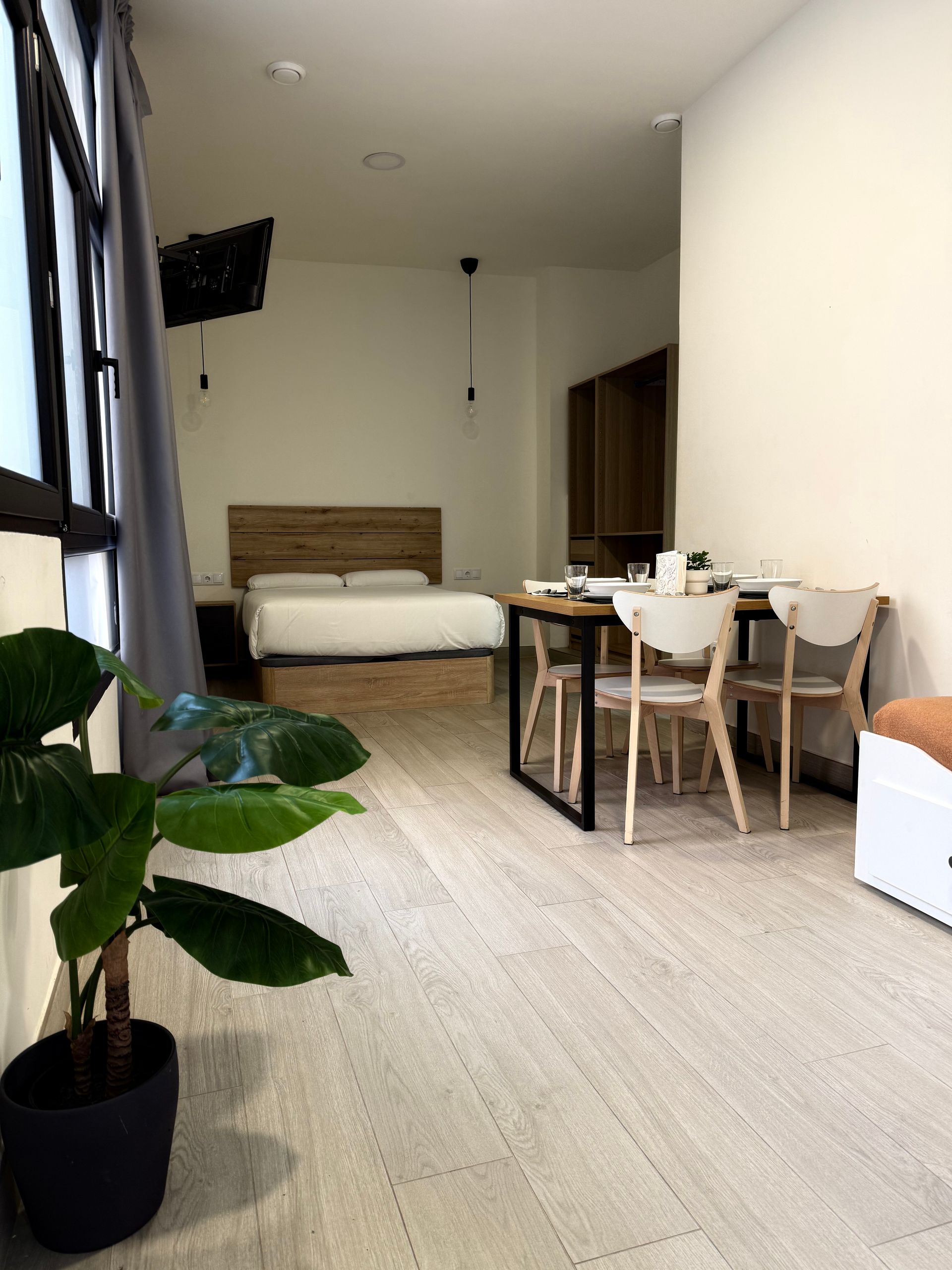 Dormitorio amplio con sofá cama y televisión en los Apartamentos Ciudad de las Artes en Valencia