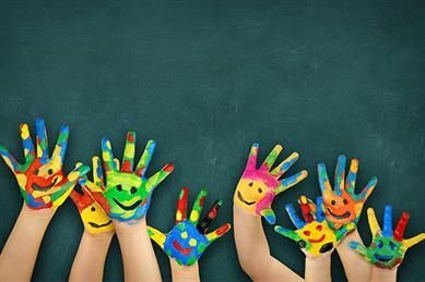 Bunte Handabdrücke mit aufgemalten Smileys vor einem dunkelgrünen Hintergrund.