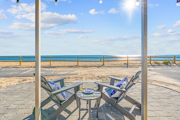 A balcony with chairs and a table overlooking the ocean.