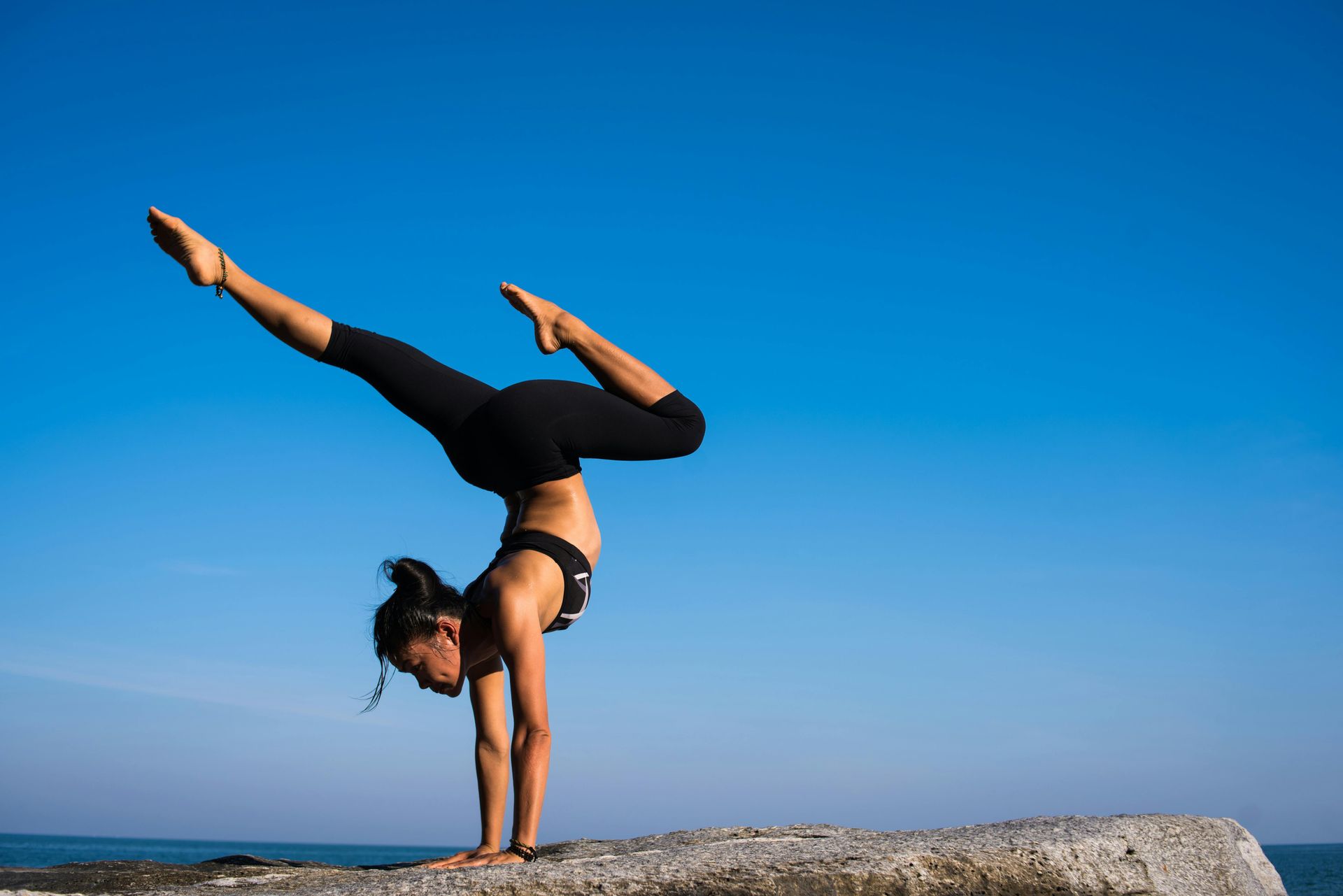 Two women are doing yoga on the beach.