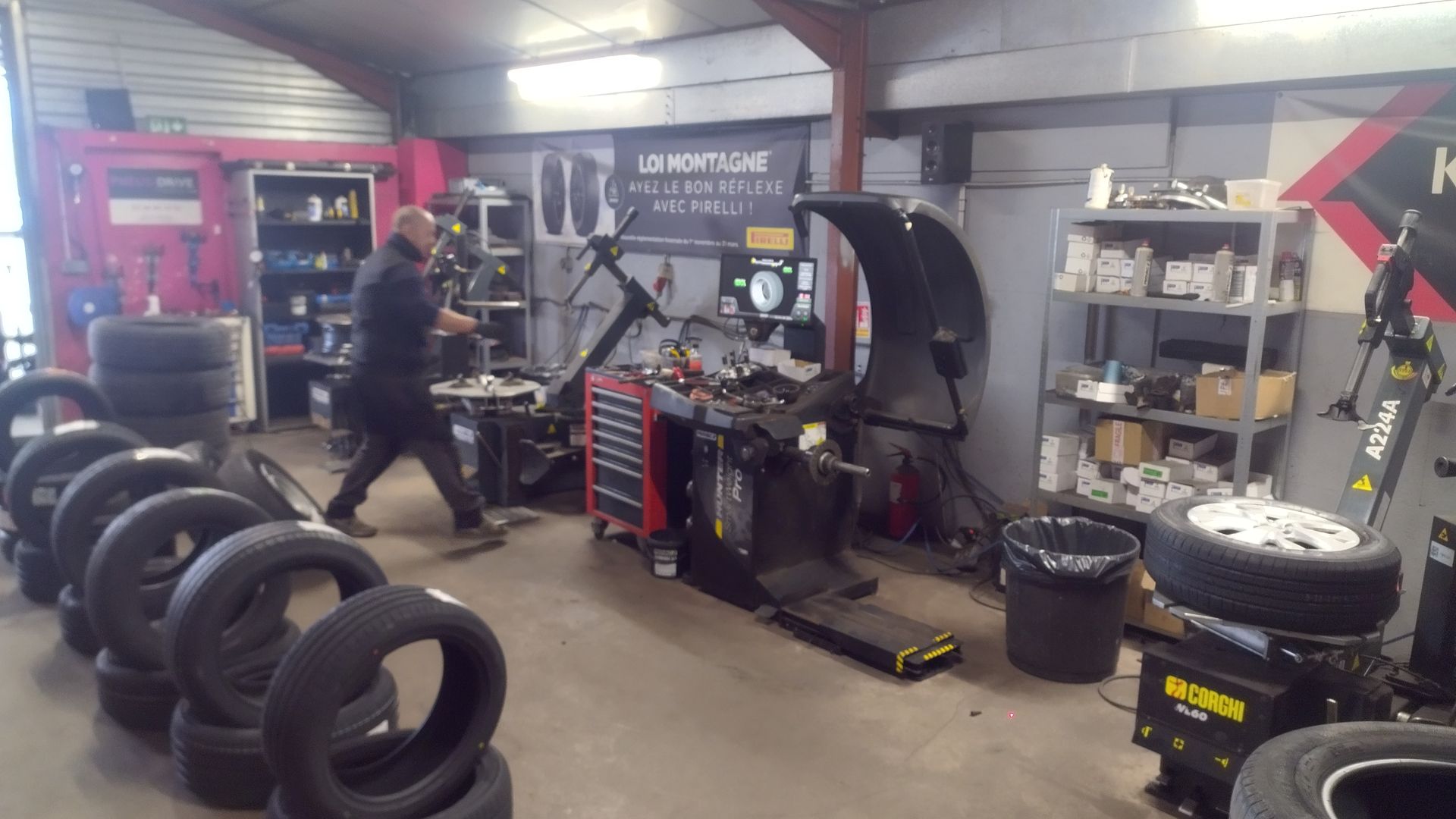 Mécanicien faisant rouler un pneu sur le sol d'un garage