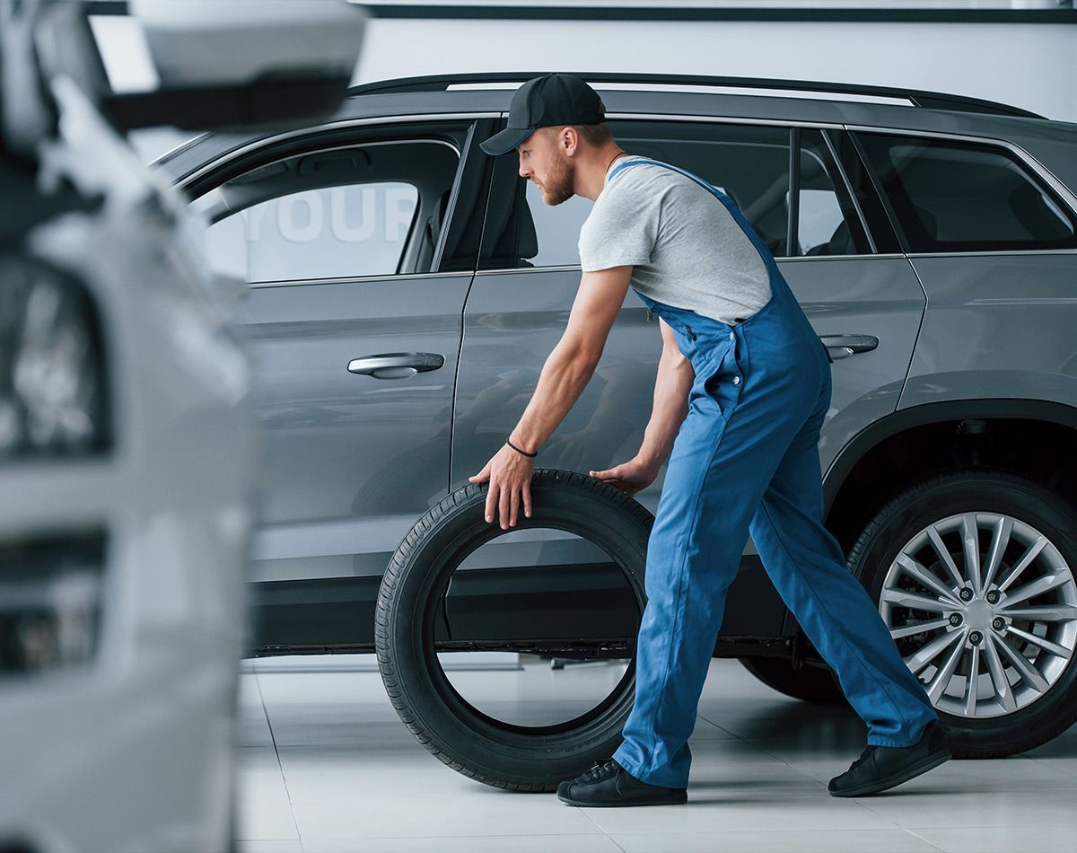 Homme poussant un pneu sur le sol d'un garage