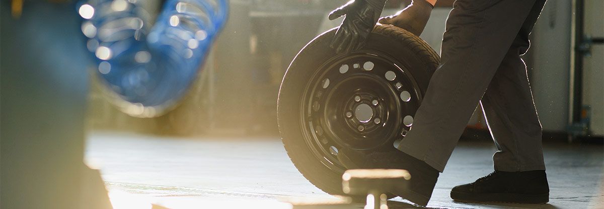 Mécanicien faisant rouler un pneu sur le sol d'un garage