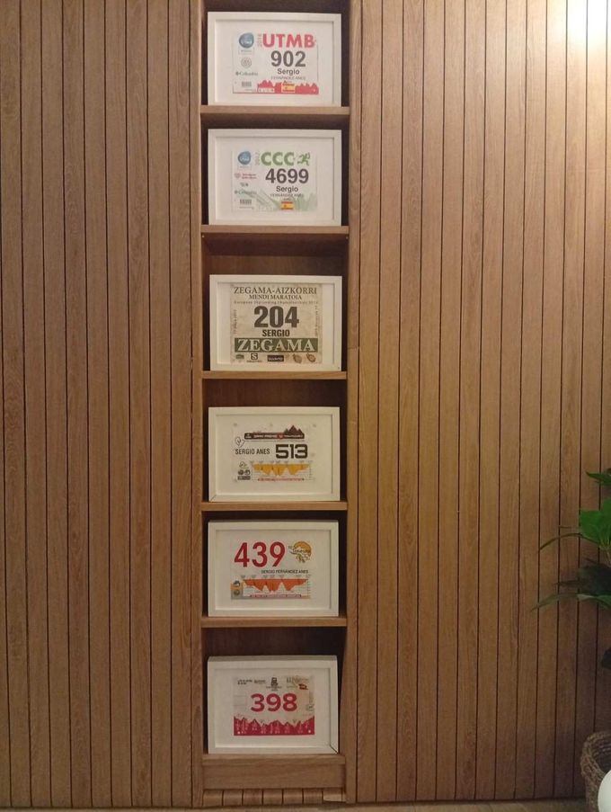 Dorsales de carrera enmarcados, expuestos en un estante de madera empotrado. Números visibles: 902, 4680, 204, 439 y 398.