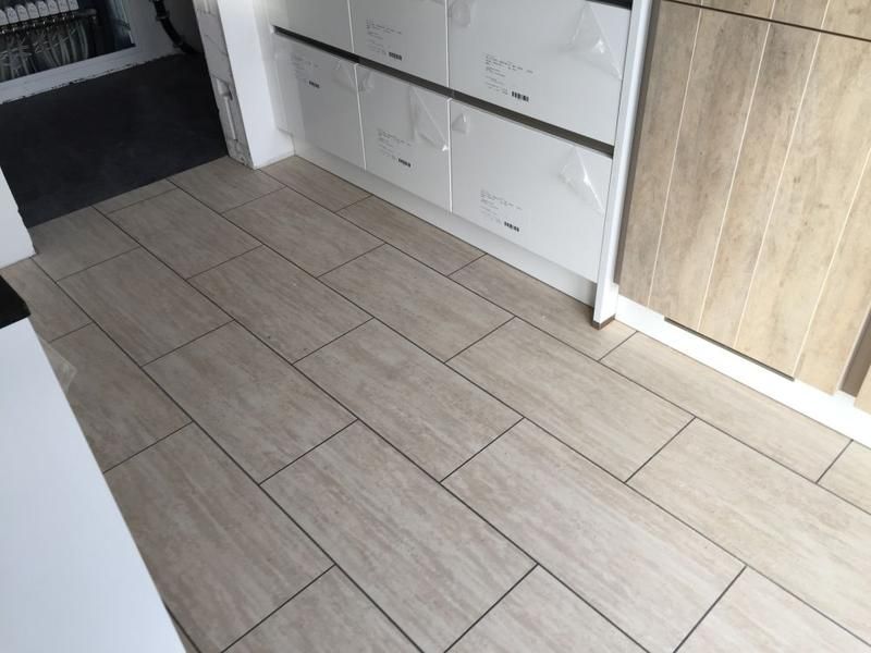 Eine Küche mit Fliesenboden und Holzschränken