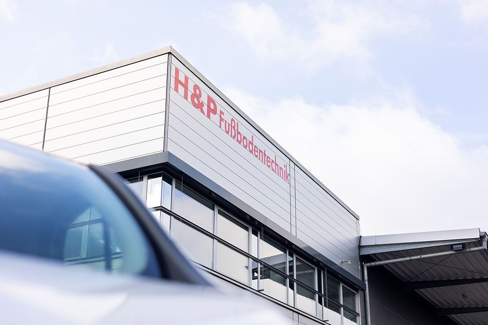 Ein Auto steht vor einem Gebäude mit der Aufschrift „h & p“
