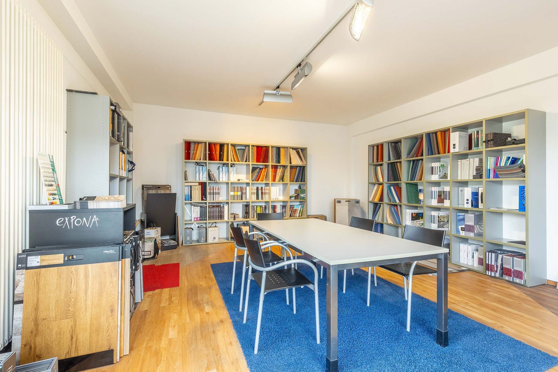 Ein großer Raum mit einem Tisch und Stühlen vor einem Bücherregal.