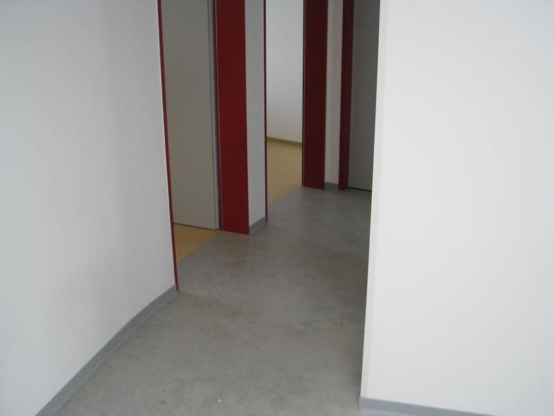 Ein Flur mit weißen Wänden und roten Türen