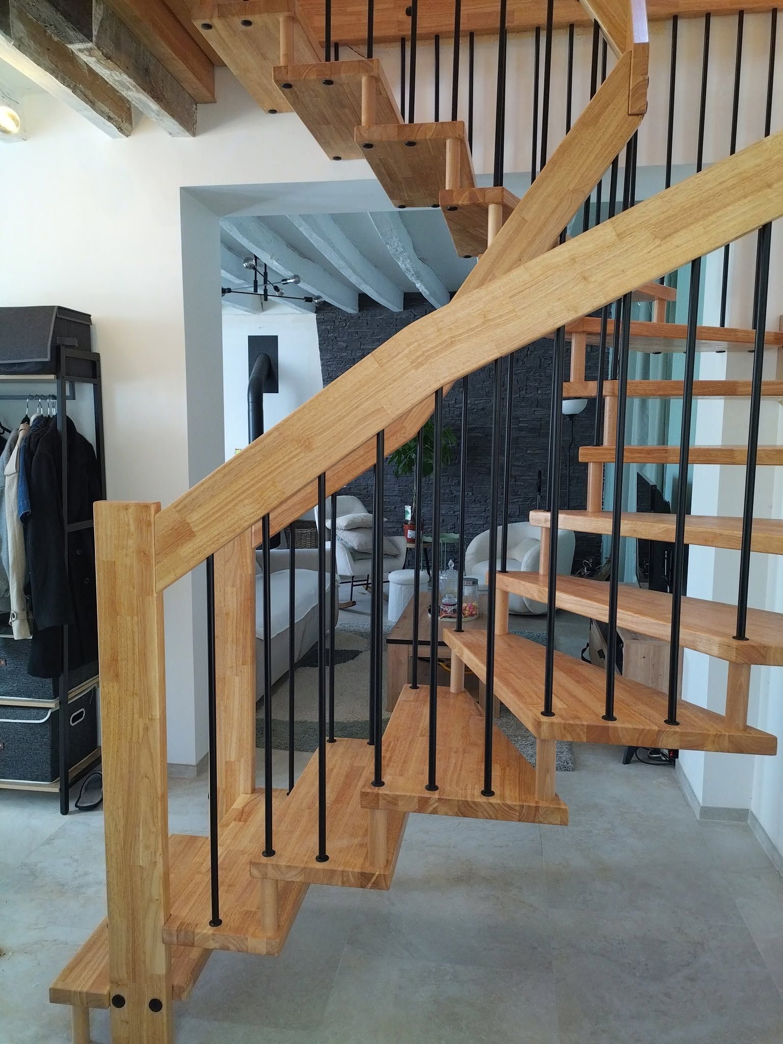 Escalier en colimaçon en bois avec des rampes en métal noir dans une pièce à l’intérieur moderne