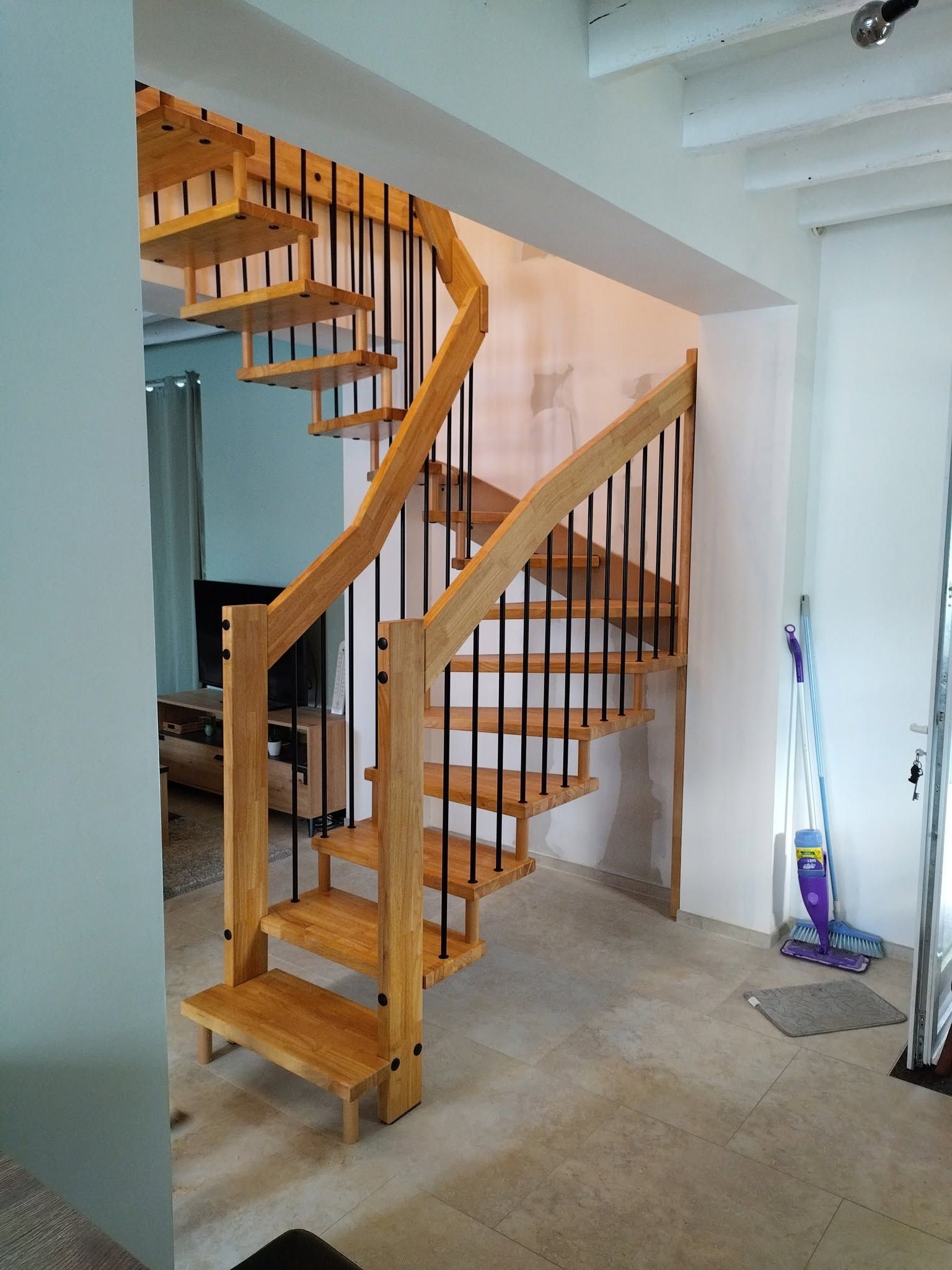 Escalier en bois incurvé avec rambardes dans un intérieur lumineux de maison