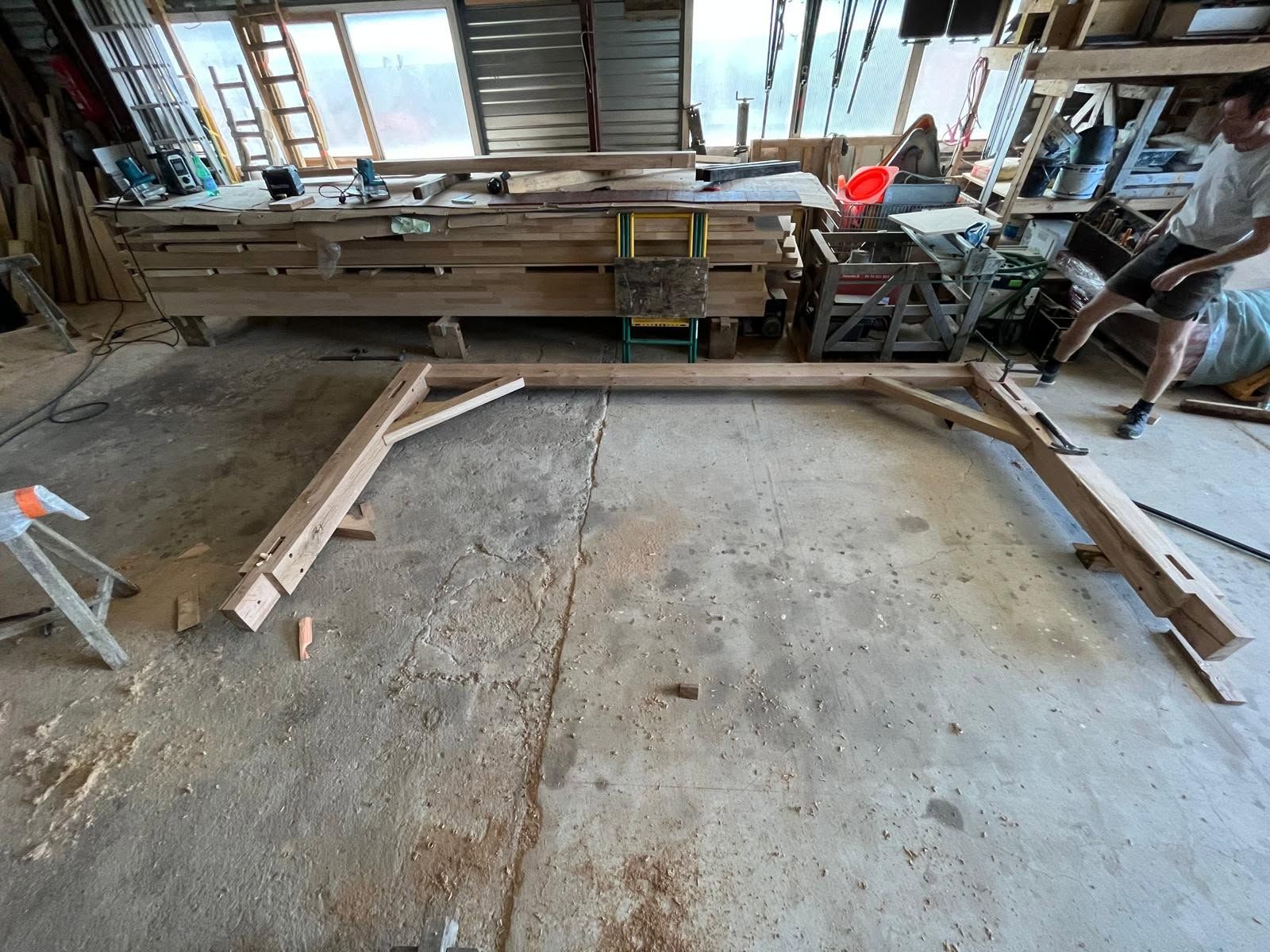 Établi en bois et outils dans un atelier poussiéreux, avec un grand cadre rectangulaire au sol