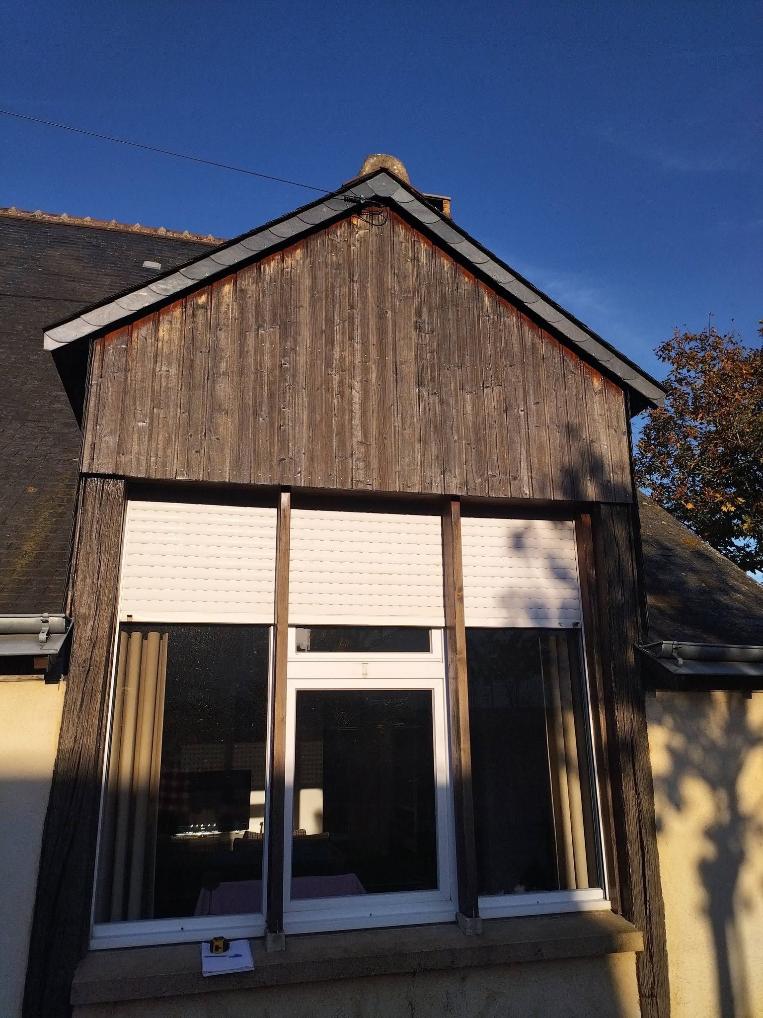 Petite boutique rustique à la façade en bois patiné et aux grandes fenêtres, sous un ciel bleu dégagé.