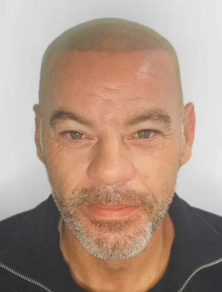 Hombre con cabeza rapada y barba incipiente mirando hacia adelante; camisa negra.