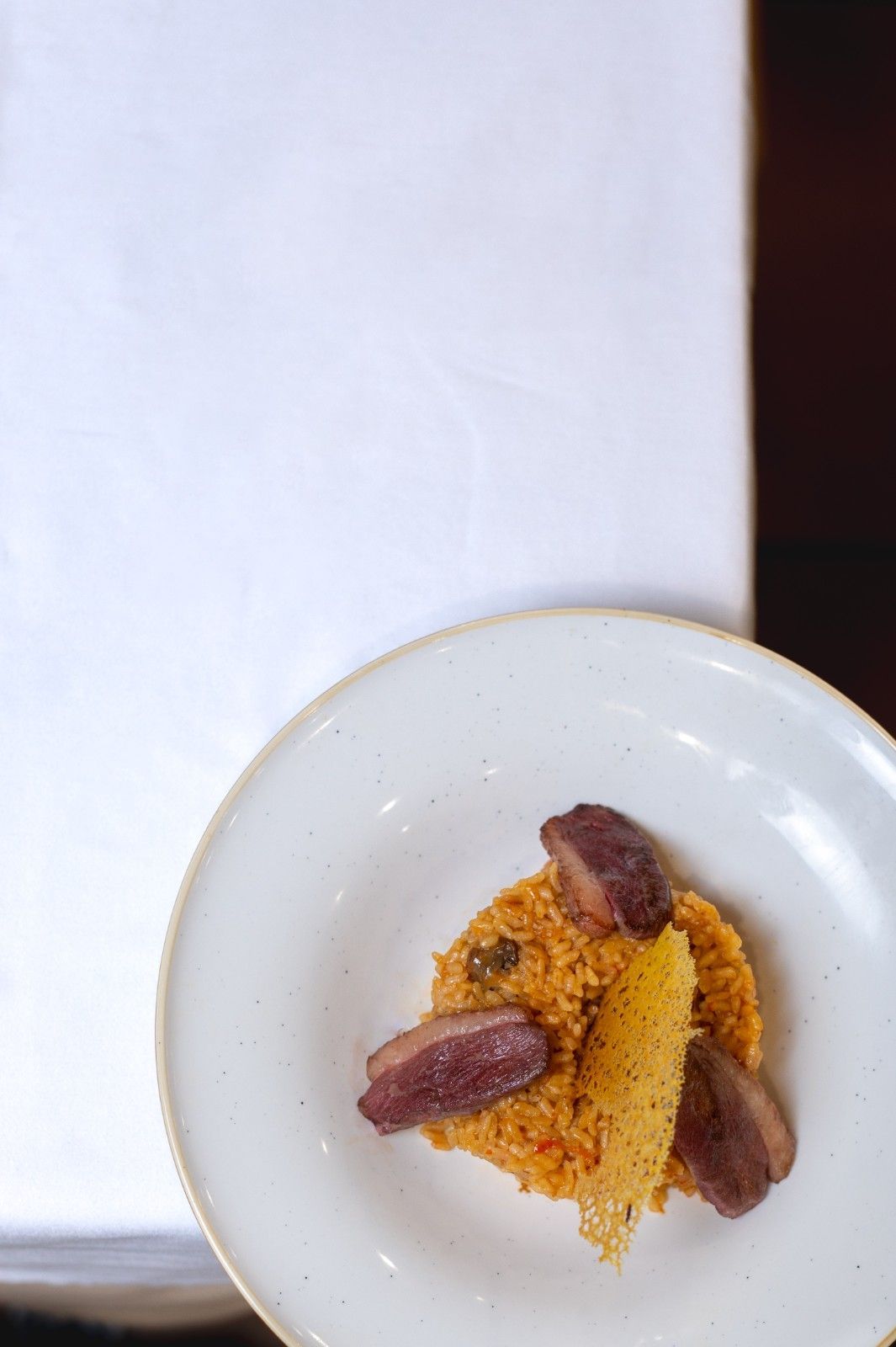 Plato con postre de naranja cubierto con dátiles sobre un mantel blanco.