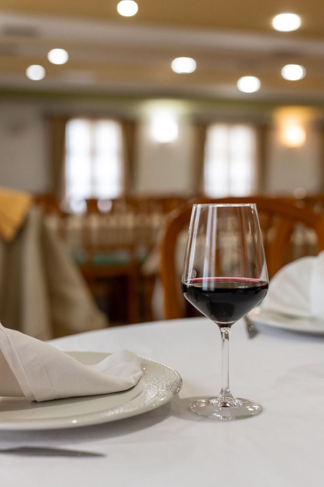 Una copa de vino sobre una mesa puesta en un restaurante con iluminación tenue.