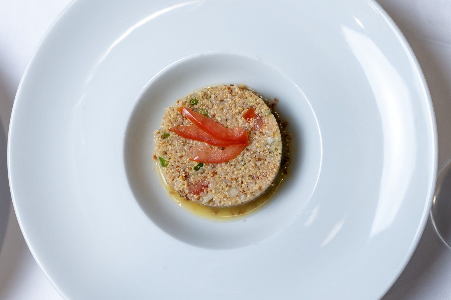 Risotto cremoso cubierto con tiras de pimiento rojo en un plato blanco.