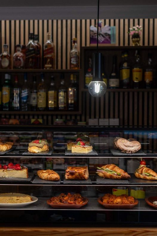 Vitrina de panadería con pasteles y tartas variadas en el interior de una tienda con iluminación cálida.