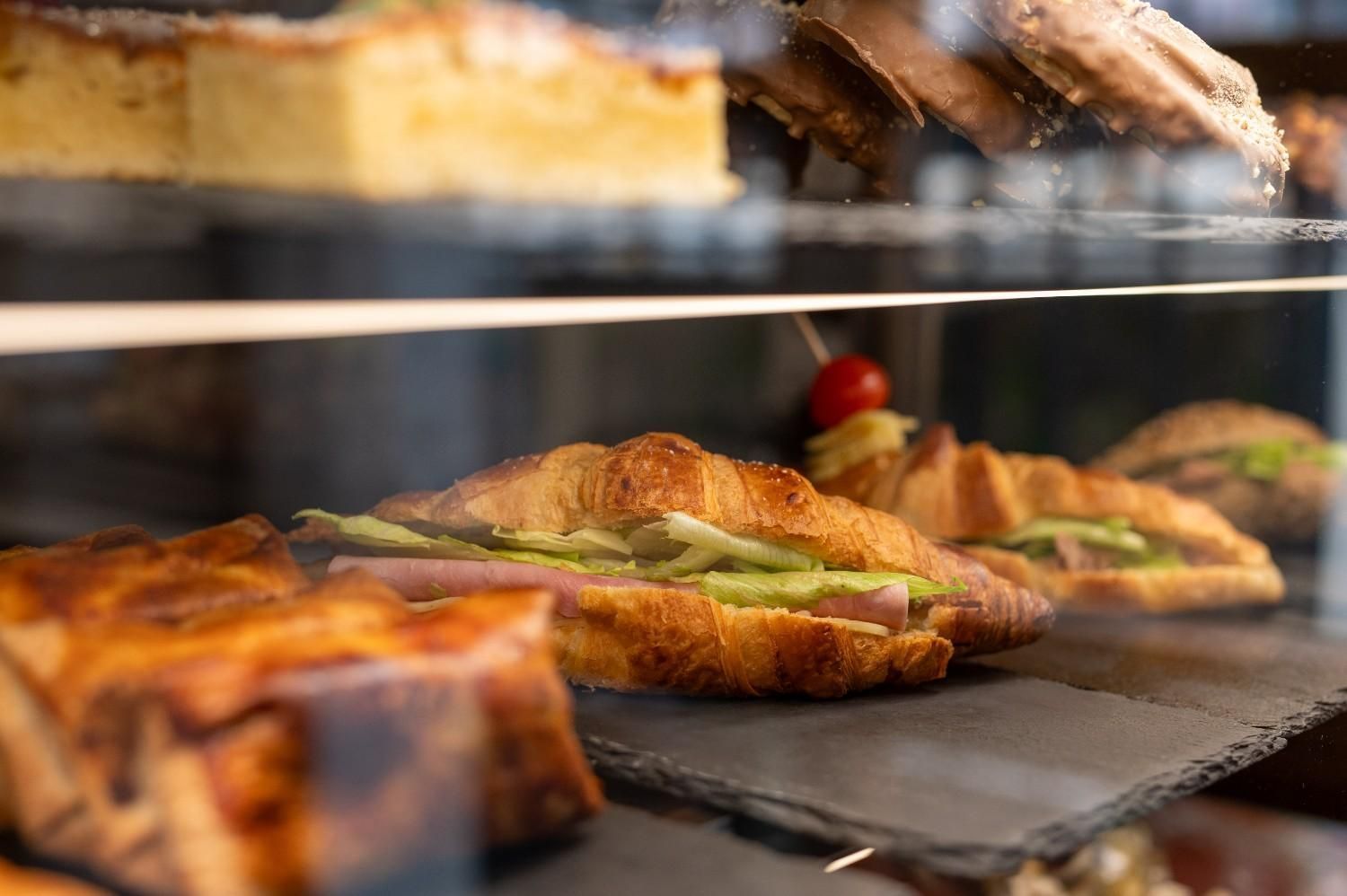 Variedad de pasteles y tartas expuestos en una estantería de panadería tras un cristal.