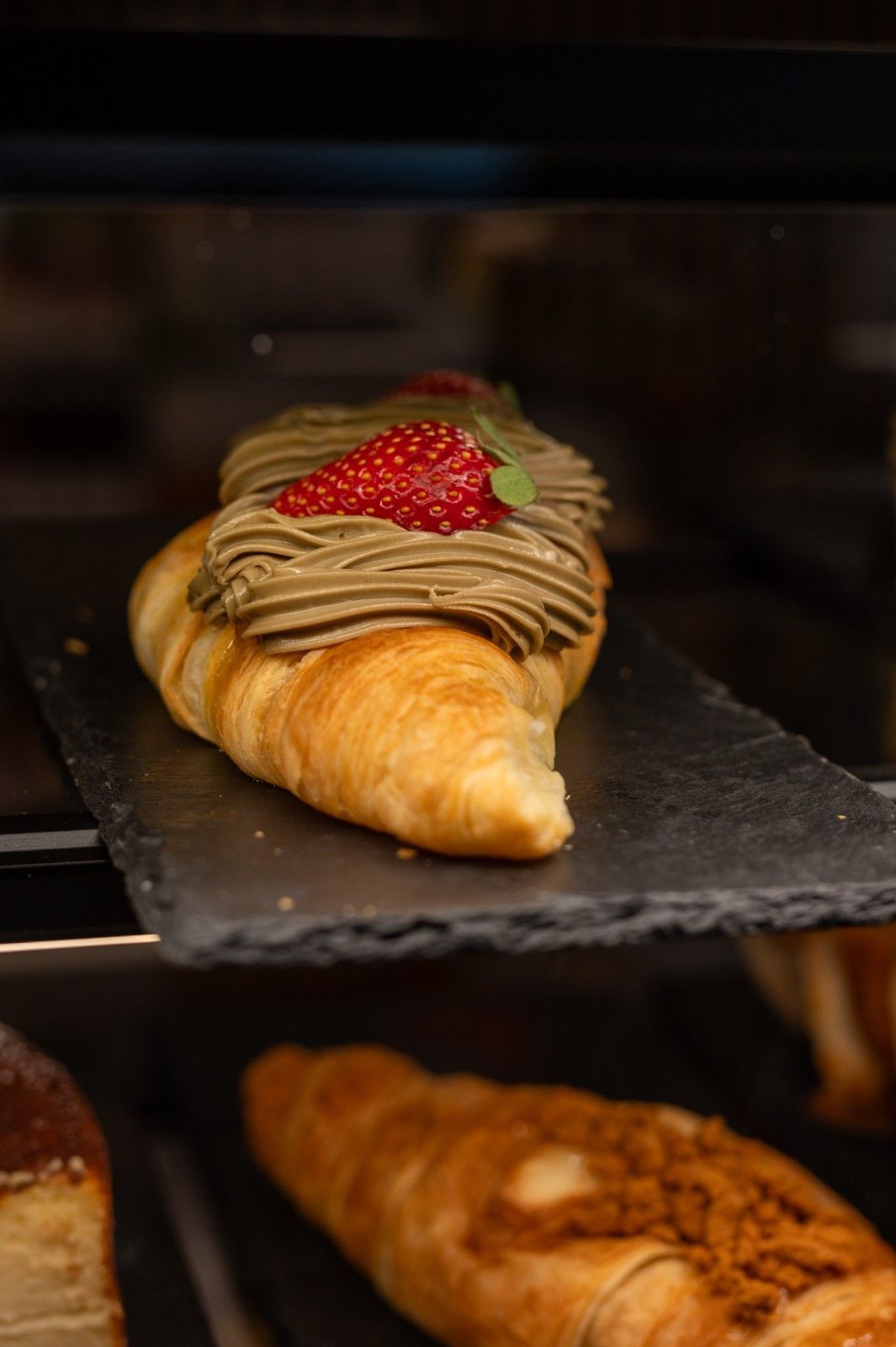 Estantería de panadería con pasteles cubiertos con glaseado de chocolate y frutos rojos.