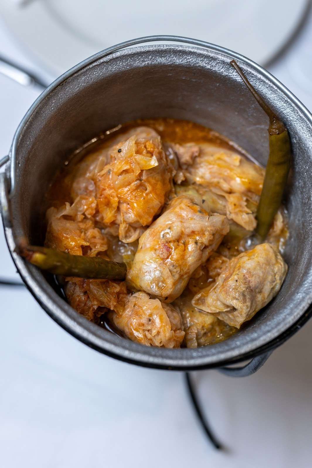 Bol de estofado de pollo con hierbas en una olla de metal, visto desde arriba.