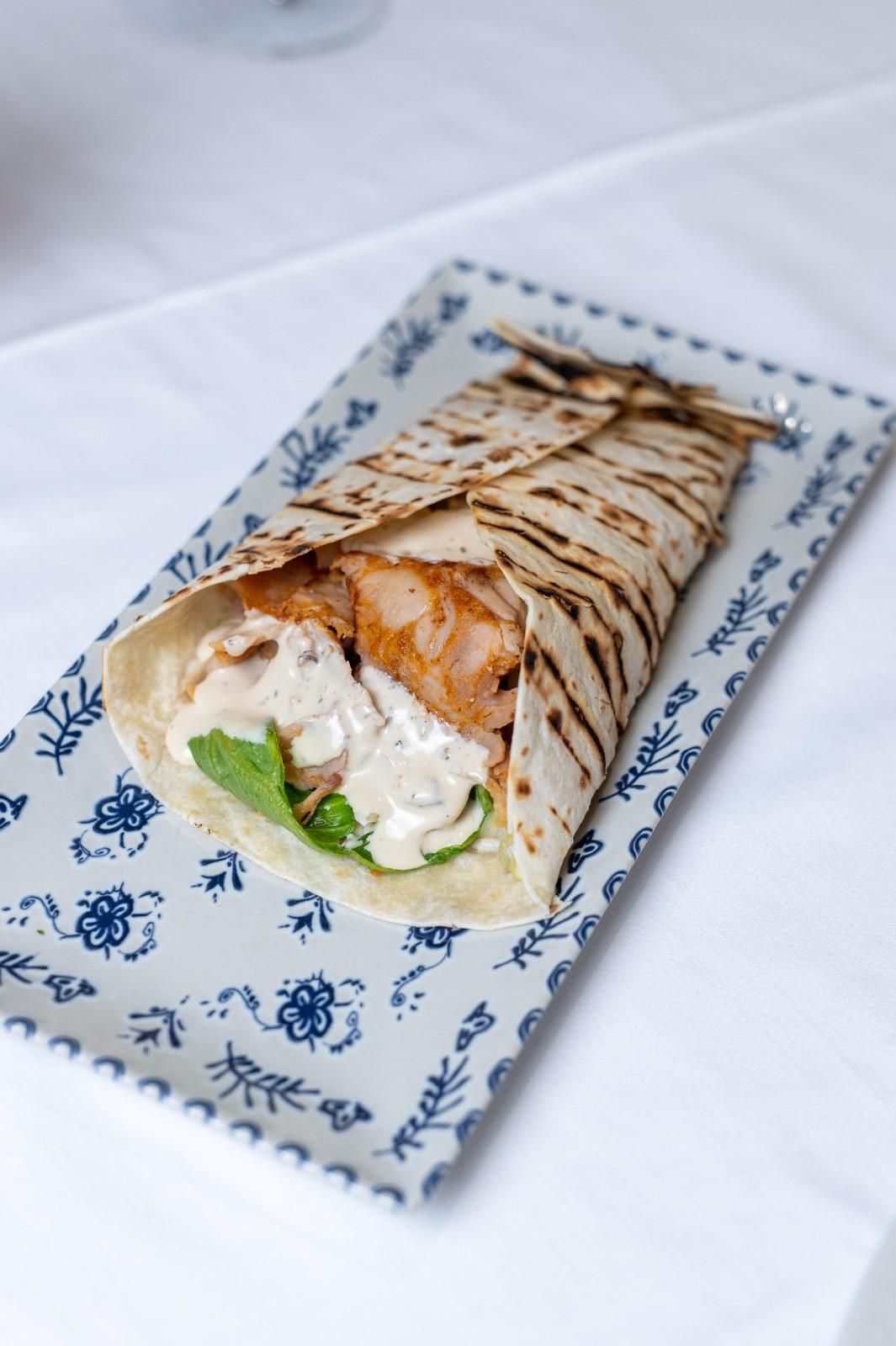Wrap a la parrilla con pollo, lechuga y salsa en un plato estampado.