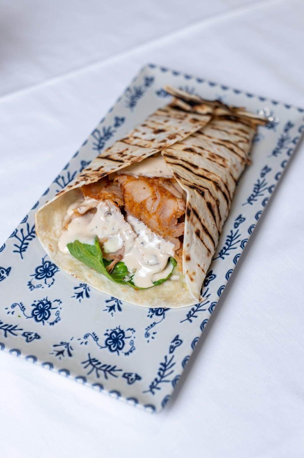 Sándwich envuelto en un plato con estampado azul y blanco.