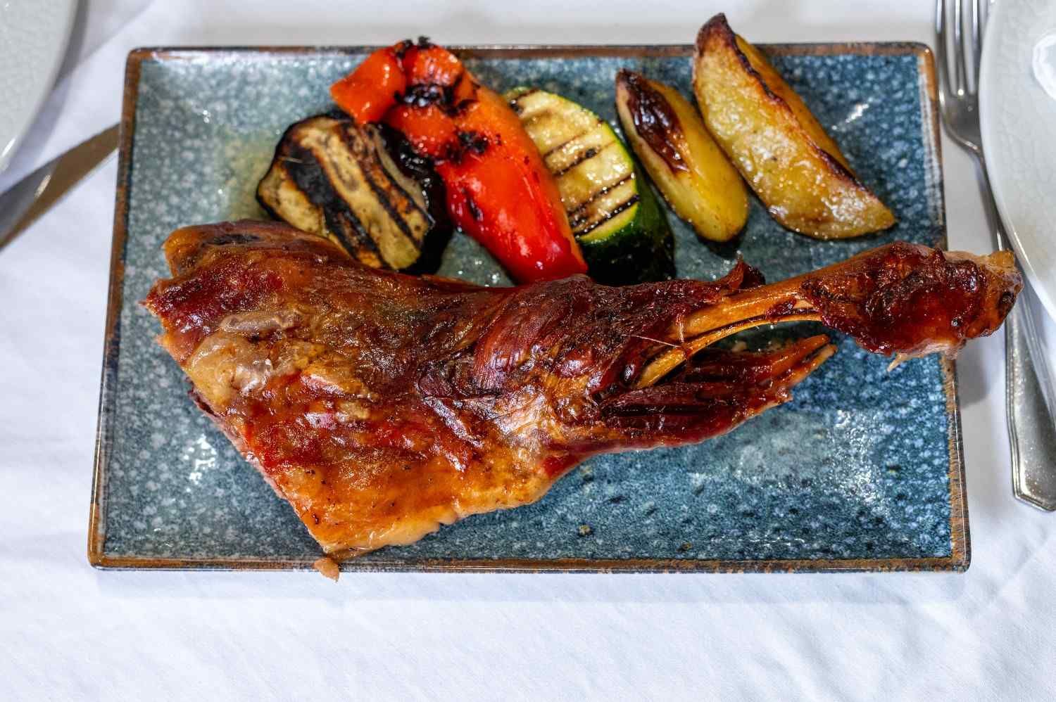 Pescado a la parrilla con verduras asadas en un plato rectangular.