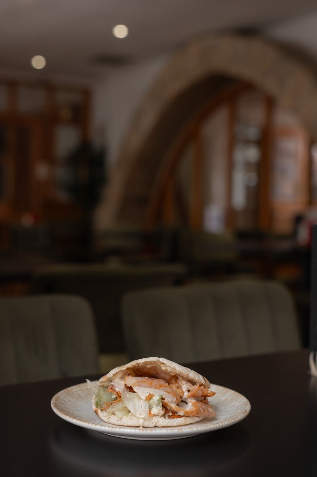 Plato de sándwiches apilados sobre una mesa en un restaurante con poca luz, con cabinas borrosas y un arco al fondo.