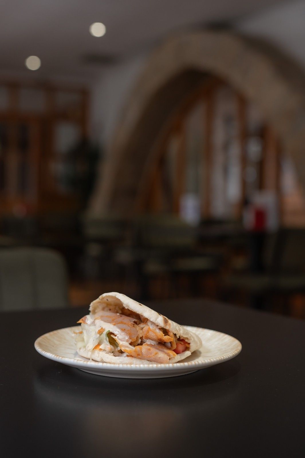 Plato con un sándwich de postre sobre una mesa oscura en un ambiente de restaurante borroso.