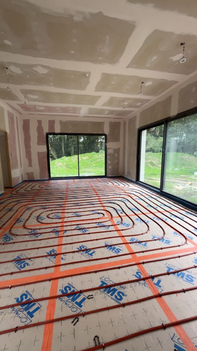 Pièce en cours d'aménagement avec installation d'un chauffage au sol radiant à tubes rouges.