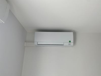 Unité de climatisation blanche fixée sur un mur blanc dans un coin.