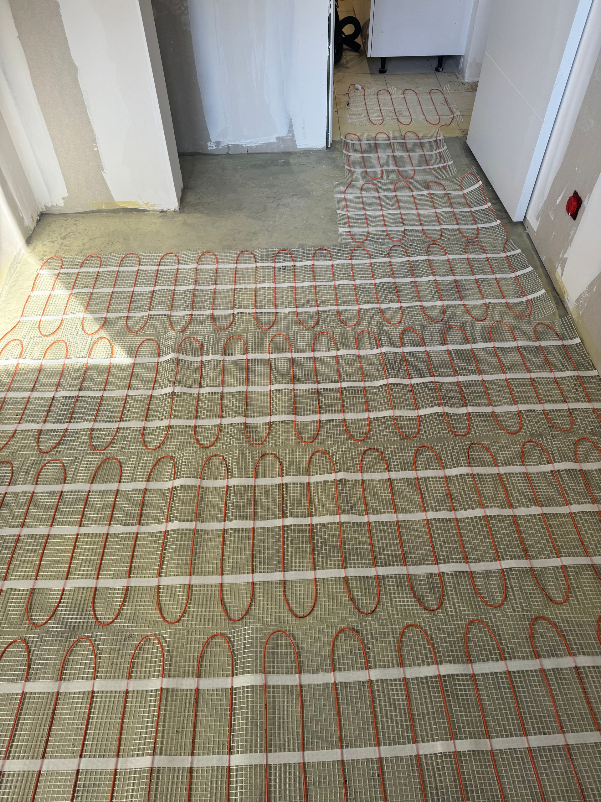 Couloir avec un circuit électrique menant à une porte carrelée et des murs blancs