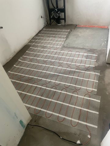 Sol carrelé avec un tapis en caoutchouc rayé menant à une petite rampe dans un couloir étroit