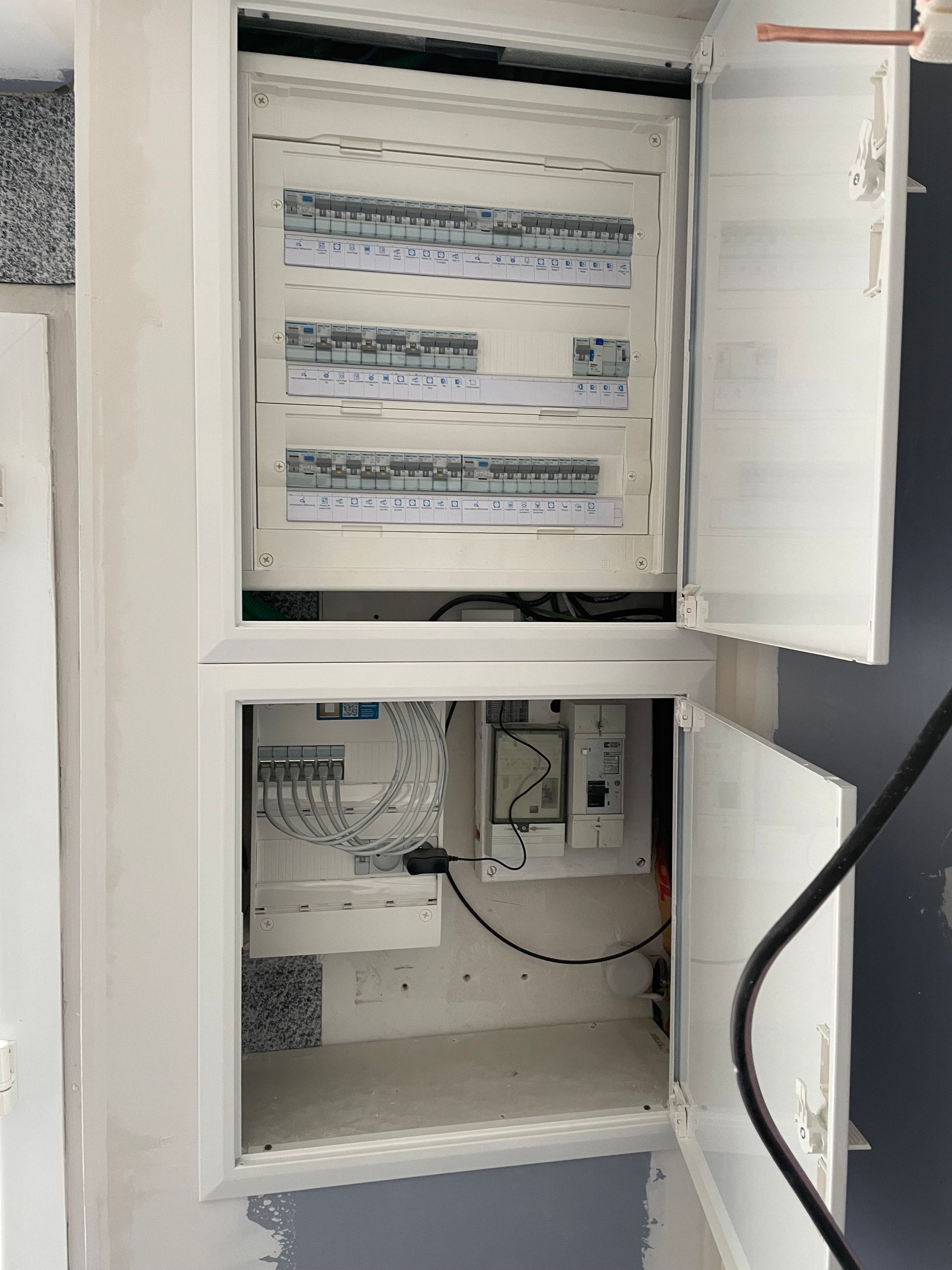 Armoire électrique ouverte avec câblage et disjoncteurs, compartiments supérieur et inférieur visibles