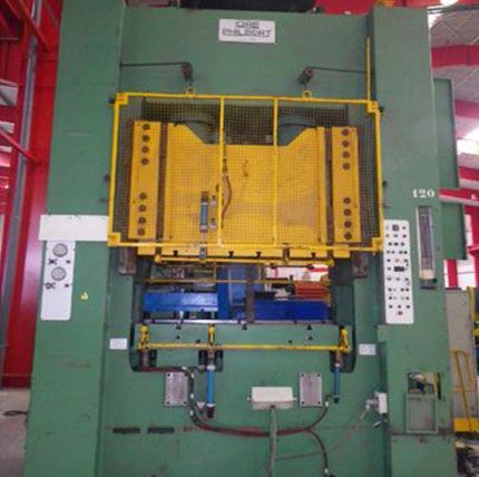 Machine industrielle avec protection de sécurité jaune sur une presse d'usine verte.