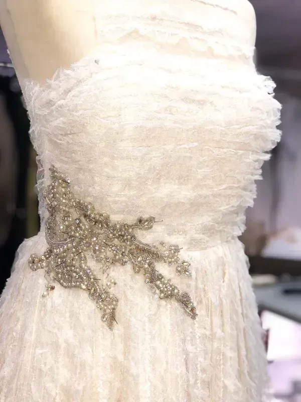 Vestido blanco sin tirantes sobre maniquí con adorno de cuentas en el lateral.