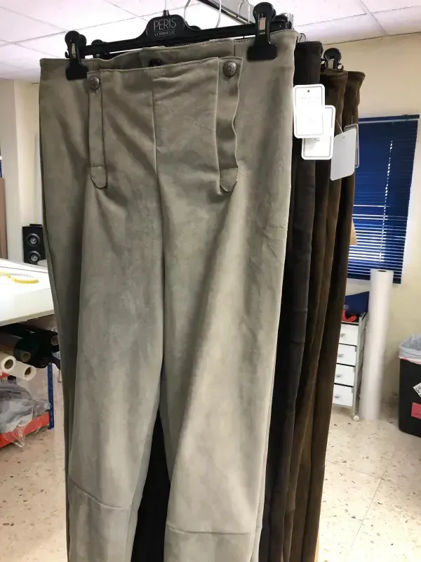 Pantalones de gamuza color canela colgados en un perchero, con pantalones marrones a la derecha.