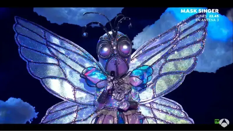 Disfraz de mariposa en el escenario, con vestido y alas iluminadas.