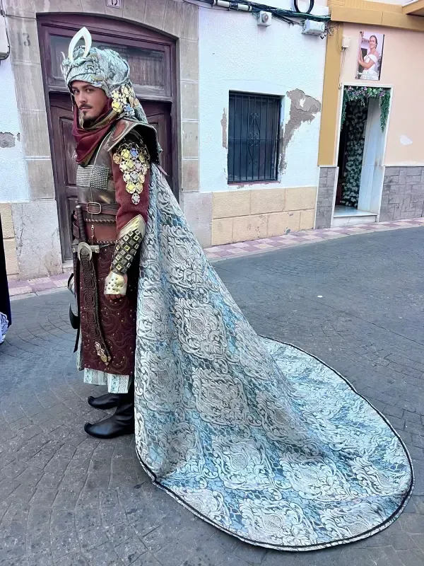 Hombre con traje histórico adornado, con cola larga, de pie en la calle.