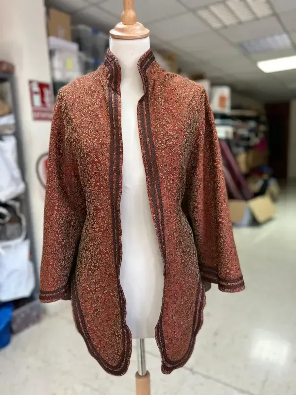 Chaqueta texturizada de color óxido sobre un maniquí en un entorno de taller.