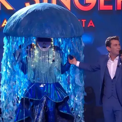Una medusa disfrazada en el escenario con una persona disfrazada, posiblemente de un concurso. La medusa es azul.