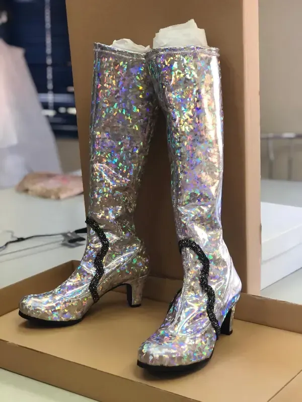 Par de botas plateadas y brillantes hasta la rodilla en una caja de cartón.